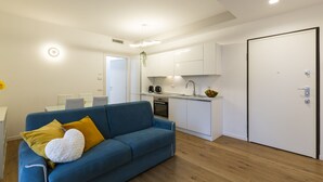 A modern apartment with a blue sofa, a white door, and a kitchen area. - notaMi - Little West (Milan)