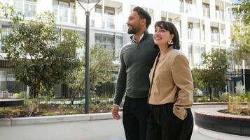 A couple standing in an urban outdoor area with a modern building in the background.