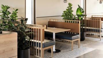 Un restaurante moderno con cabinas de madera, asientos acolchados negros y plantas en macetas.