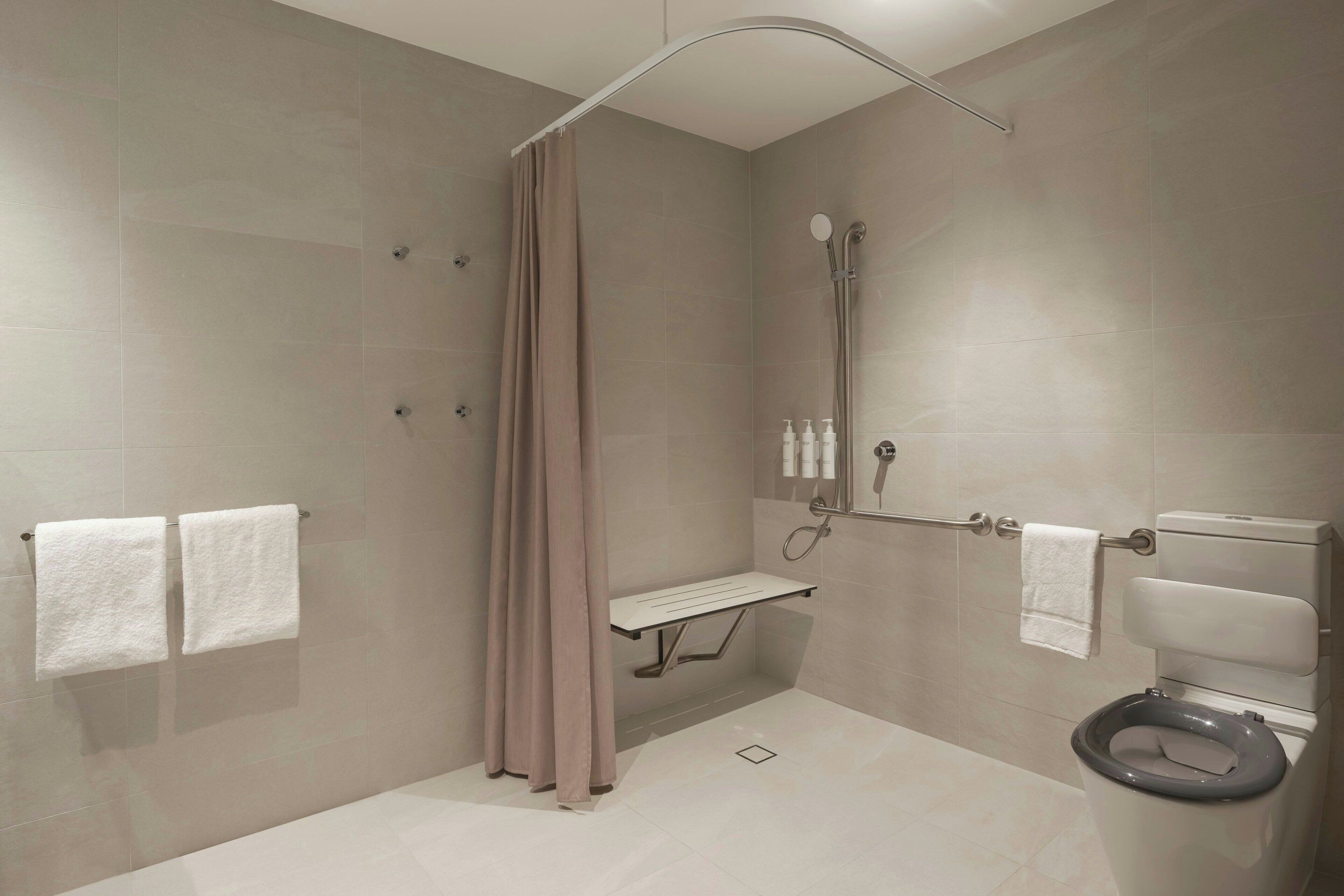 Un baño moderno con ducha, inodoro y una banca.