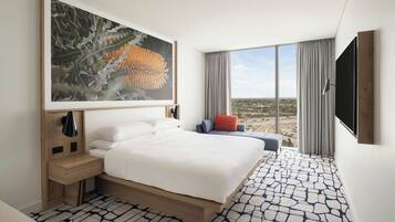 Une chambre d’hôtel moderne dotée d’un grand lit, d’un bureau, d’une chaise et d’une grande fenêtre donnant sur la ville.