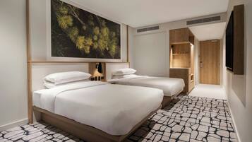 Habitación de hotel con dos camas, un cuadro grande con motivos forestales, un armario de madera y un televisor.