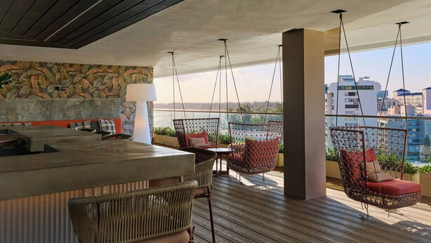 A modern interior with a bar area, wicker furniture, and a view of the city. - Casa Costera, Isla Verde Beach, Apartments by Marriott Bonvoy (Carolina)