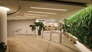 A modern lobby with a green vertical garden, a reception desk, and a staircase. - Casa Costera, Isla Verde Beach, Apartments by Marriott Bonvoy (Carolina)