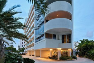 Un hotel moderno con una estructura de varios pisos, zona de estar al aire libre y palmeras.