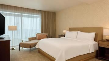 A hotel room with a large bed, a desk, a chair, and a TV.