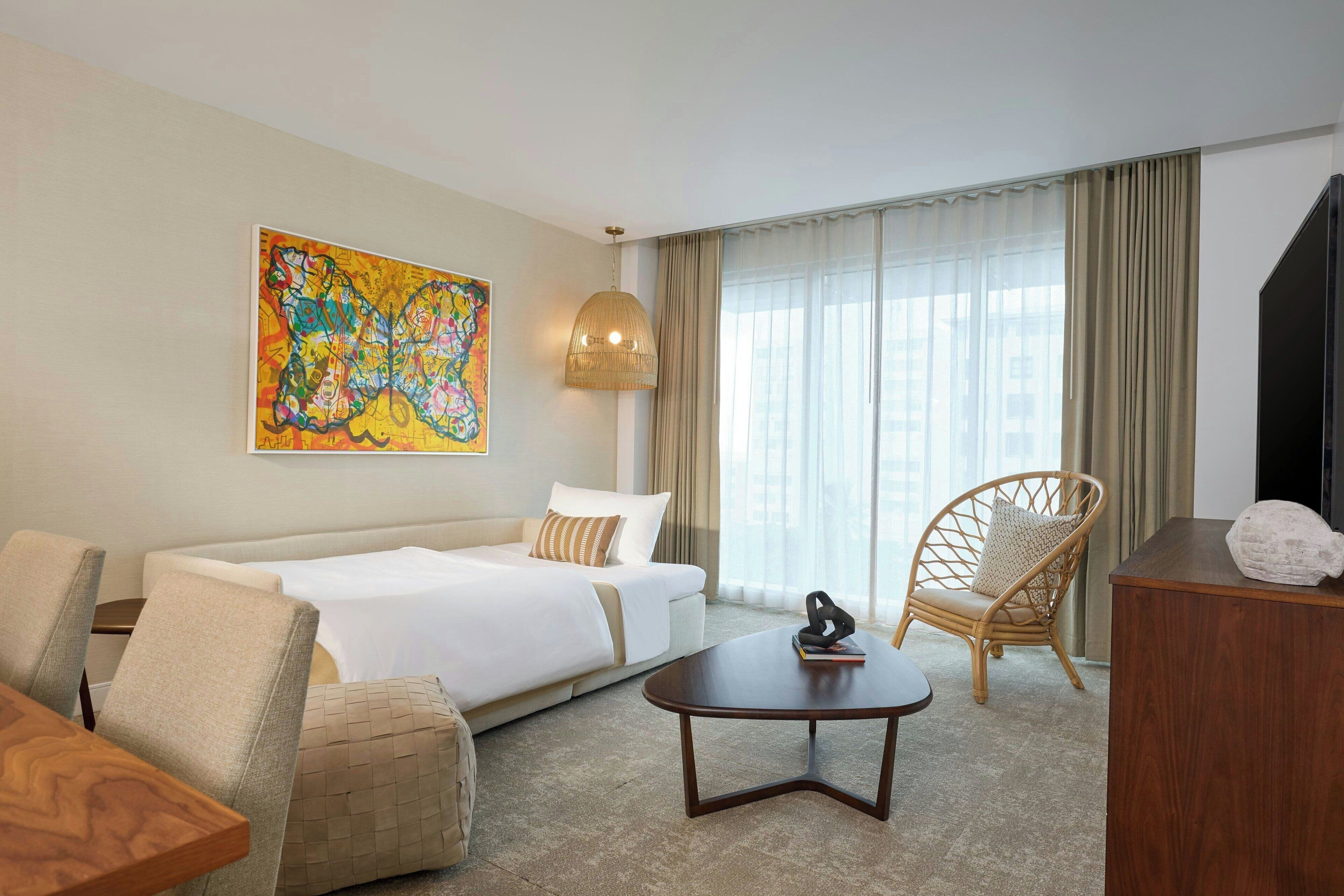 Een hotelkamer met een bed, een bank, een stoel, een bijzettafeltje en een schilderij aan de muur.