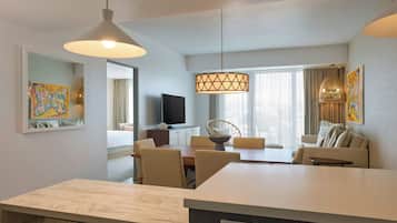 Ett modernt hotellrum med en matplats, en soffa, en TV och konstverk på väggarna.