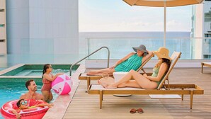 A poolside area with lounge chairs, a pool, and a view of the ocean. - Casa Costera, Isla Verde Beach, Apartments by Marriott Bonvoy (Carolina)