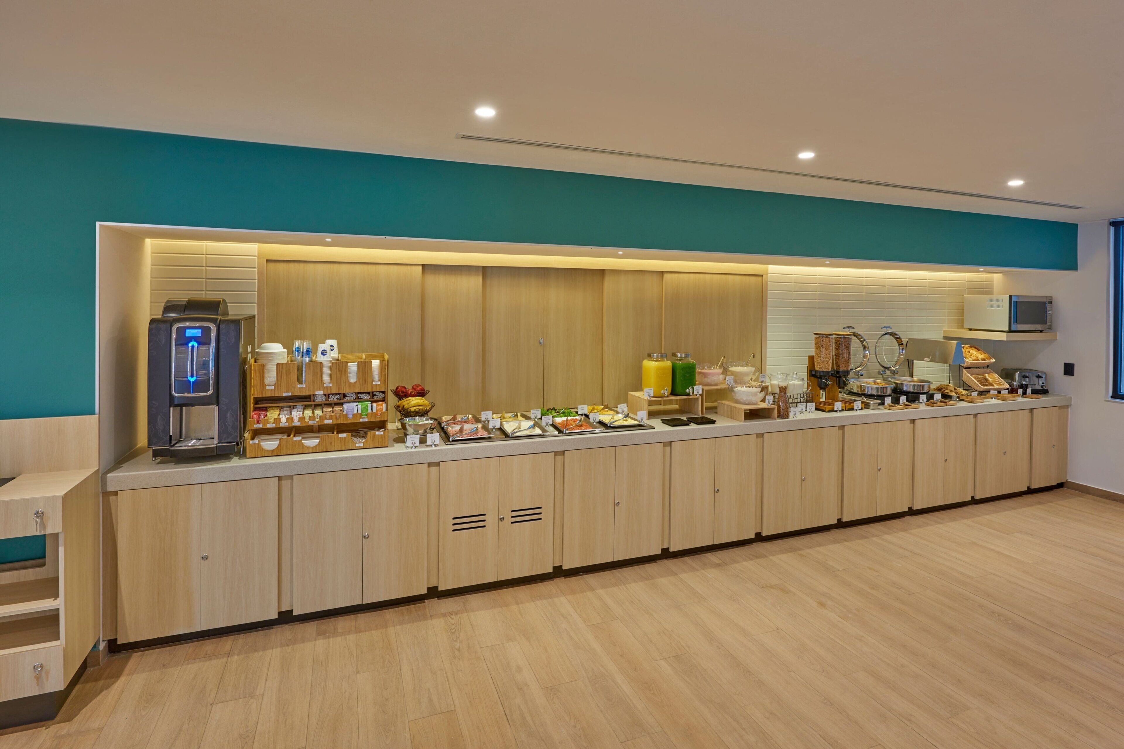 A long counter with a coffee machine, various food items, and a microwave.