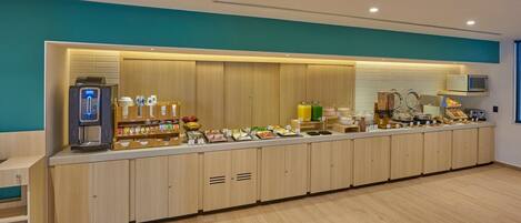 A long counter with a coffee machine, various food items, and a microwave.