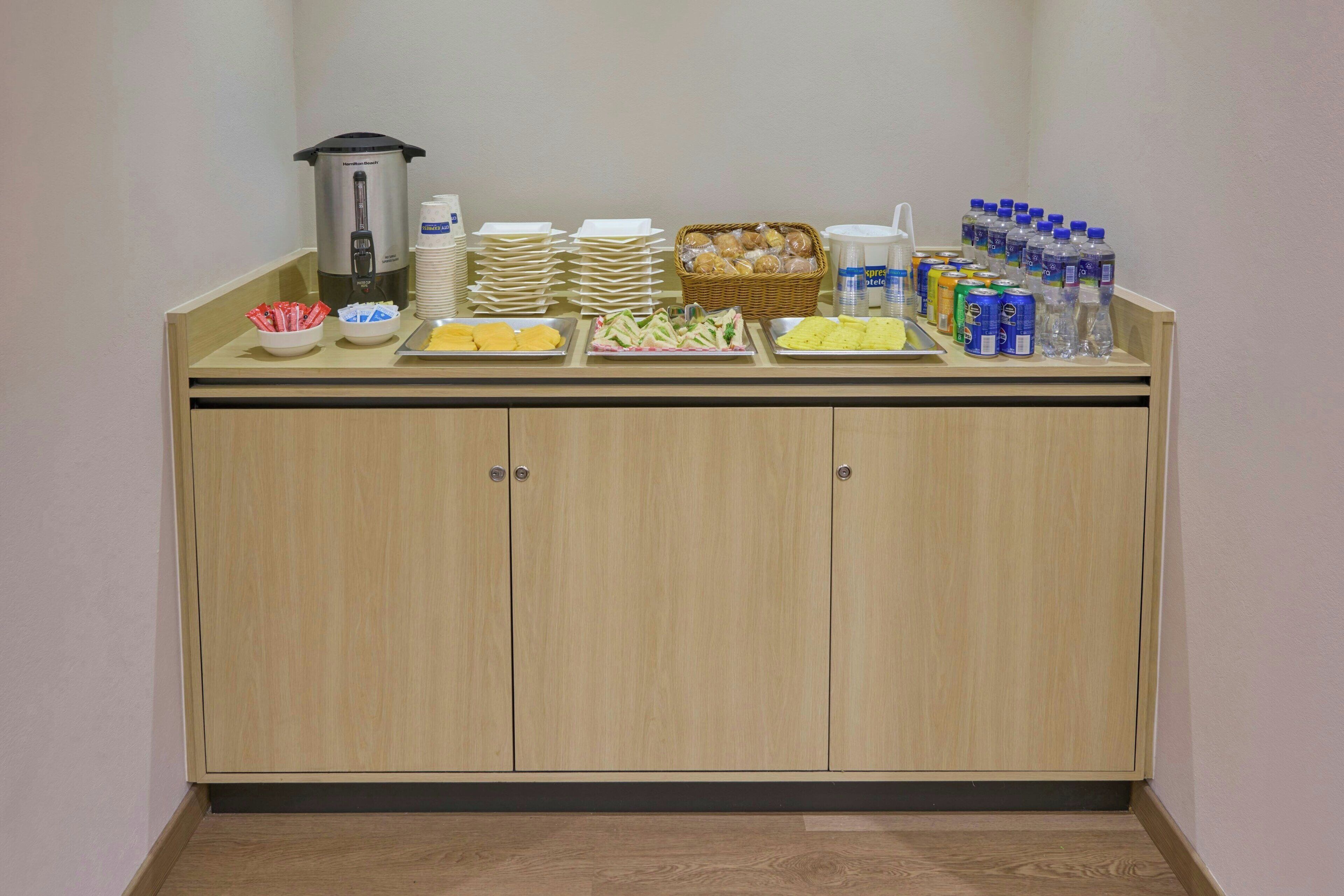 A buffet setup with various food items, beverages, and a coffee maker.