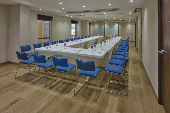A conference room with a long table, blue chairs, and water bottles.