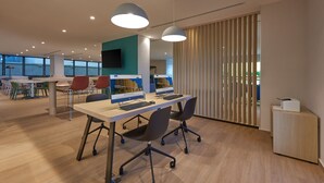 Un espacio de oficina moderno con una mesa larga, dos computadoras y sillas de oficina.