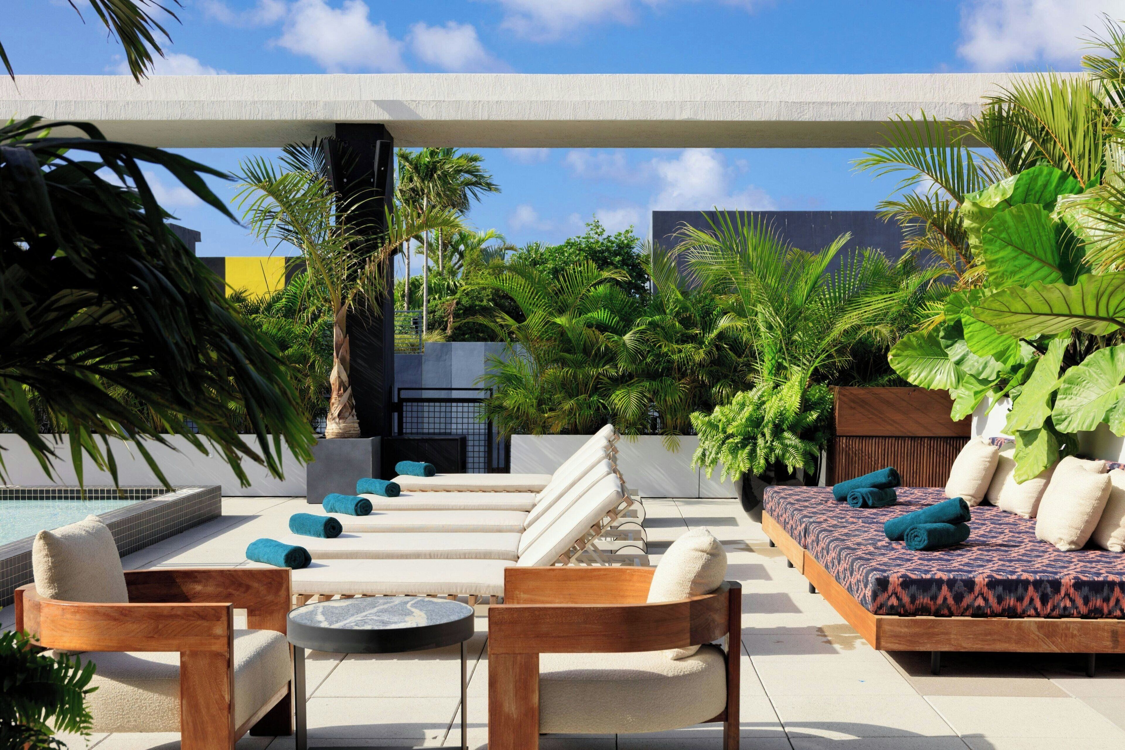 Terraza en la azotea con piscina, sillas de descanso, un banco de madera y diversas plantas.