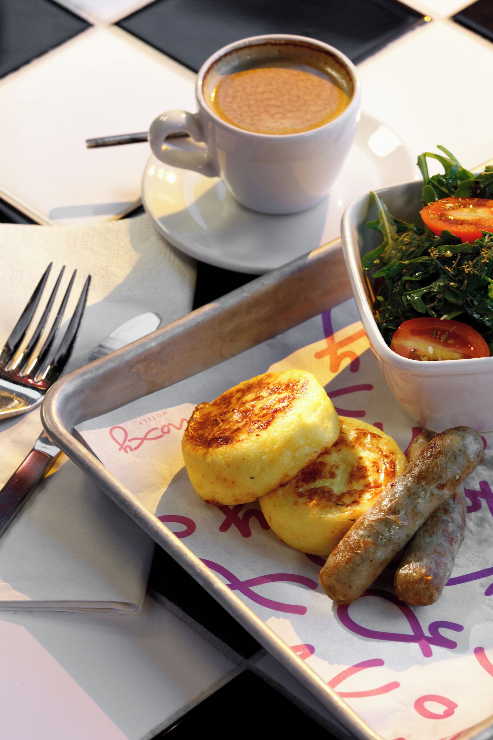 Ein Tablett mit Speisen, darunter eine Kaffeetasse, eine Schüssel mit Salat und ein Gebäckstück.