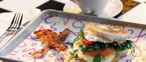 A sandwich on a tray with a cup of coffee in the background.