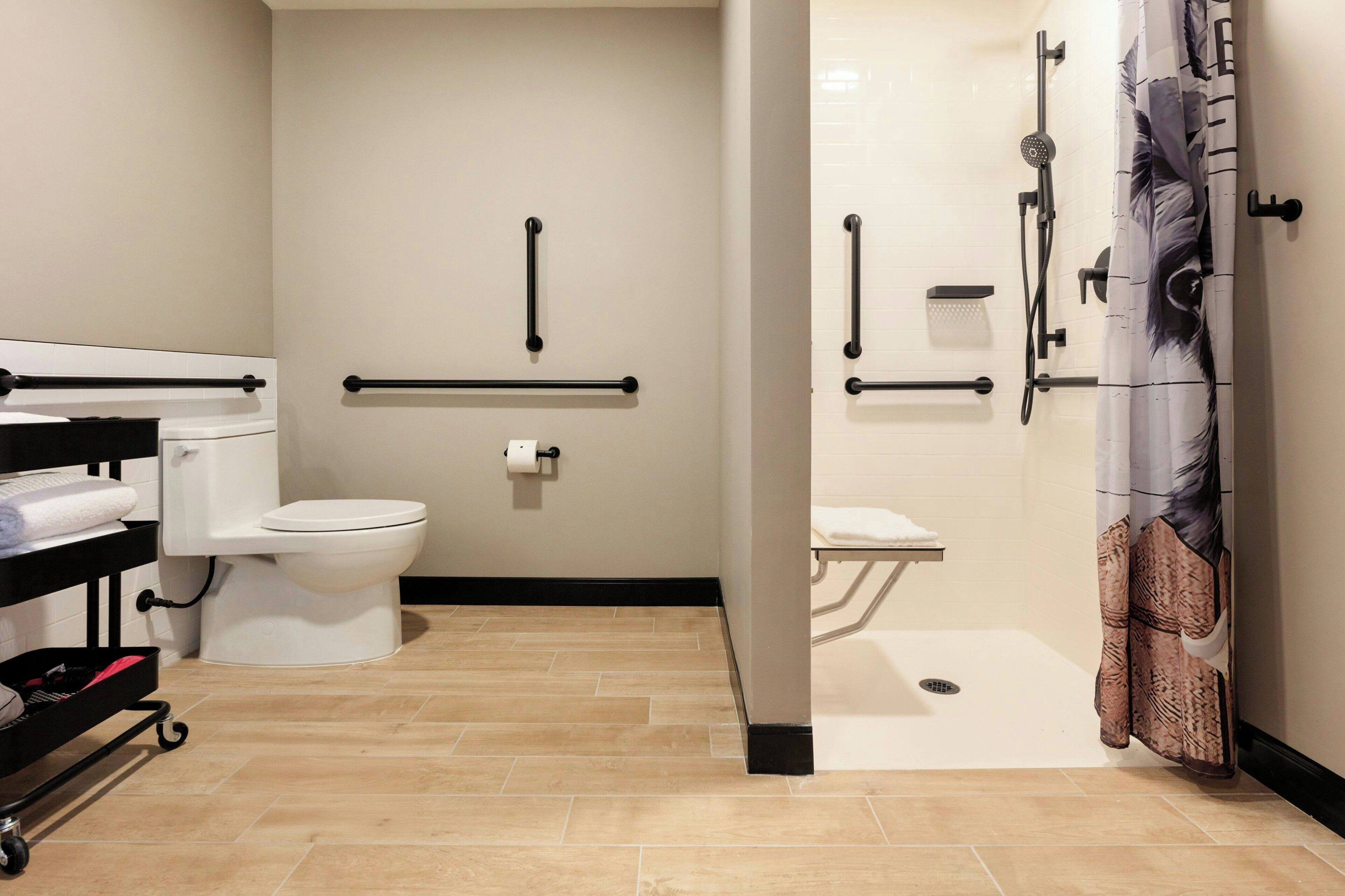 Een moderne badkamer met toilet, douche en handgrepen.