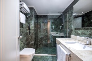 Une salle de bain moderne avec une douche à parois de verre, des toilettes blanches et un meuble-lavabo en marbre avec un évier.