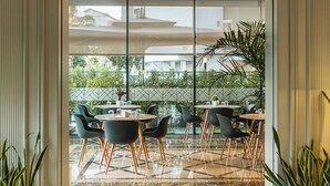 A modern hotel lobby with marble flooring, black and wooden chairs, and potted plants.