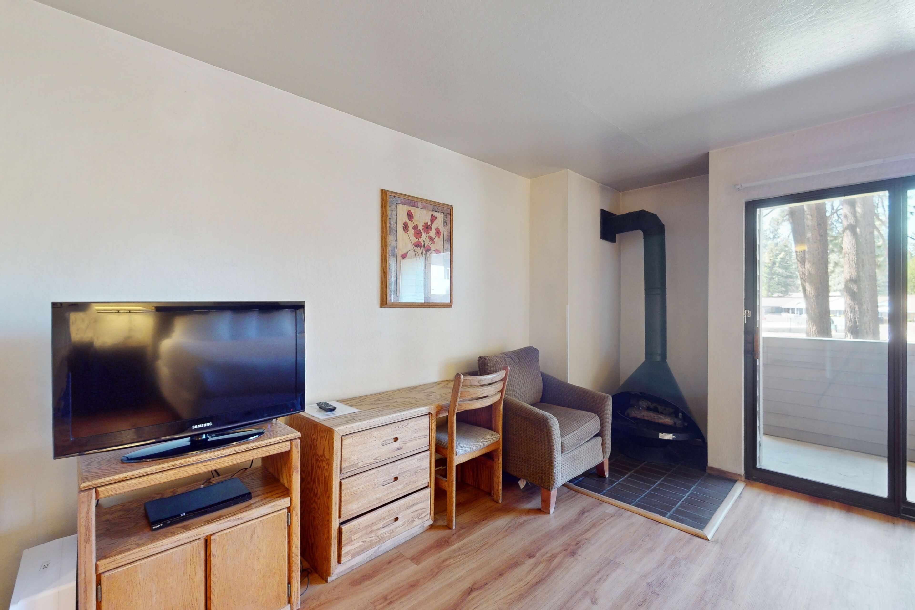 Uma sala de estar moderna com televisão de tela plana, mobiliário de madeira, um sofá e uma lareira a lenha.
