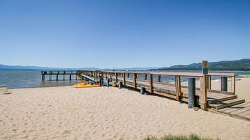 A wooden pier extending into a calm body of water, with a clear sky above.