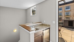 A compact kitchen with a built-in dishwasher, a small window, and a view of the outdoor patio area.