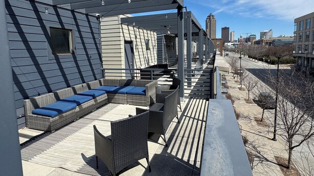 A rooftop patio with outdoor furniture, a pergola, and a cityscape view.