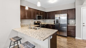 A modern kitchen with granite countertops, stainless steel appliances, and dark wooden cabinets.