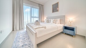 A modern bedroom with a large bed, a nightstand with a lamp, and a view of the city through the window. - Stylish 1BR with DIFC Skyline and Zabeel Views (Downtown)
