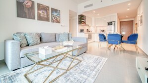 A modern living room with a grey sofa, a glass coffee table, and a blue rug. - Stylish 1BR with DIFC Skyline and Zabeel Views (Downtown)