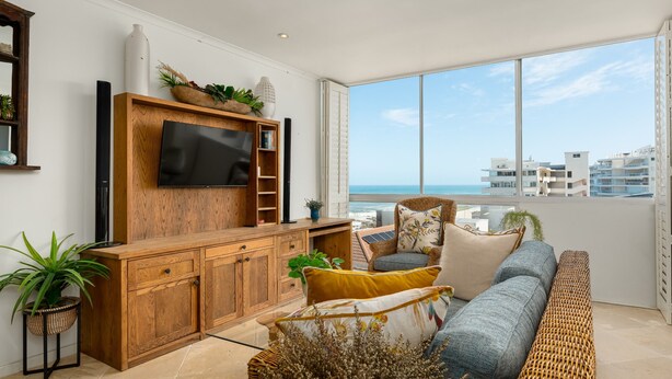 A modern living room with a large TV, wooden furniture, a sofa, and a view of the ocean. - Stunning Bantry Bay Haven - Beach on Your Doorstep (Cape Town)