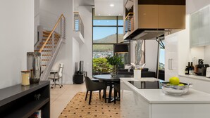 A modern kitchen with a dining area, a staircase, and a view of a cityscape. - Lux Elegance in Heart of Mouille Point (Cape Town)