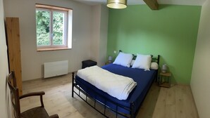 A bedroom with a bed, a window, a radiator, and a chair.