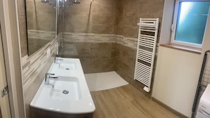 A bathroom with two sinks, a shower, and a towel rack.