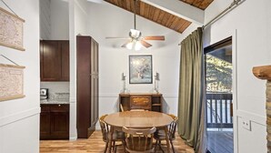 A dining area with a wooden table and chairs, a ceiling fan, and a view of the outdoors through a sliding glass door. - Sunshine Village 126: Pet friendly, Close to Green (Mammoth Lakes)