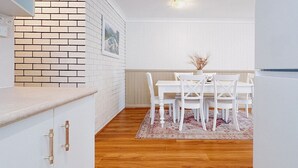 Eine Küche mit weißen Ziegelwänden, einer Holzauskleidung und einem Essbereich mit Tisch und Stühlen.