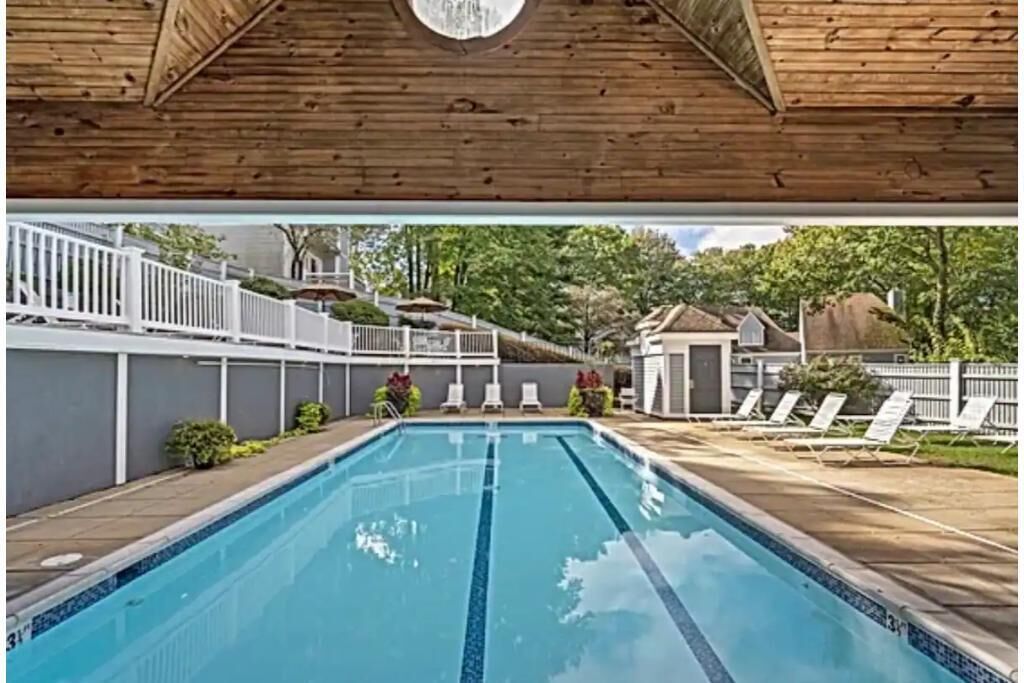A swimming pool with a wooden ceiling and a white fence surrounding it.