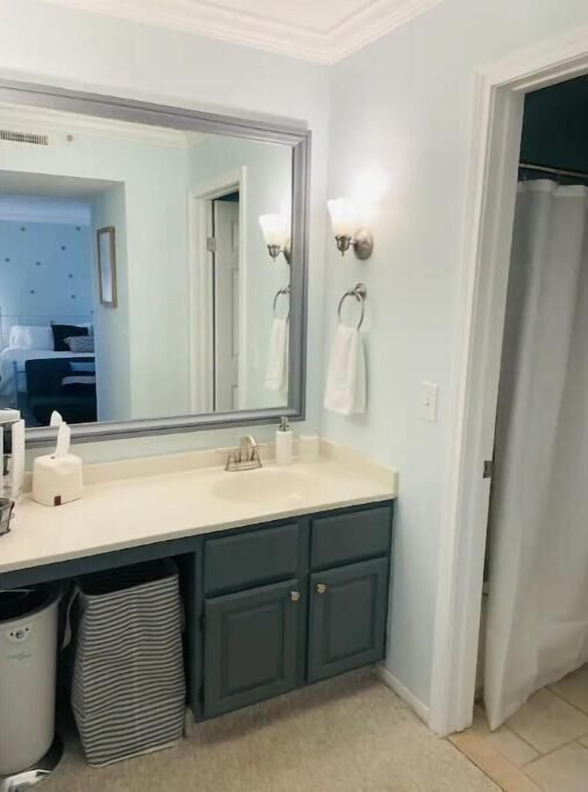 A bathroom with a large mirror, a sink, and a towel rack.