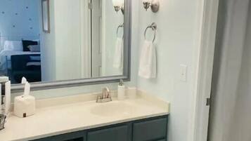 A bathroom with a large mirror, a sink, and a towel rack.