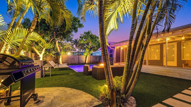 A backyard with a barbecue, a pool, and outdoor furniture.