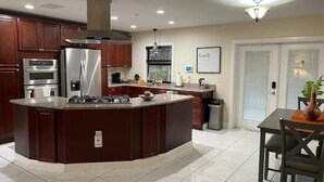 Een moderne keuken met een centraal eiland, inbouwapparatuur en een eethoek met een tafel en stoelen.