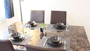 Una mesa de comedor dispuesta con platos, tazones, cubiertos y una pequeña planta en maceta.
