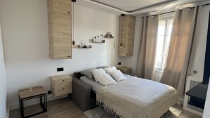 A modern bedroom with a bed, bedside tables, a wardrobe, and a window with curtains. - Charmant Appartement Joinvillais (Joinville-le-Pont)