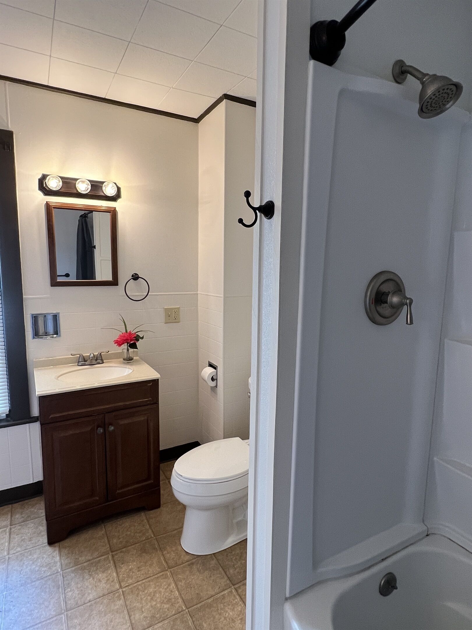 Et badeværelse med vask, spejl, toilet og brusebad.