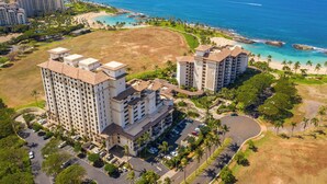 Un hotel di grandi dimensioni con numerosi piani, un parcheggio e vista sul mare.