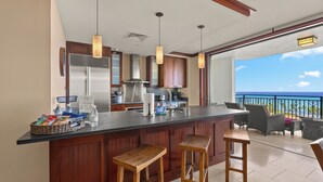 Una cucina con una grande isola, sgabelli da bar e vista sull'oceano.