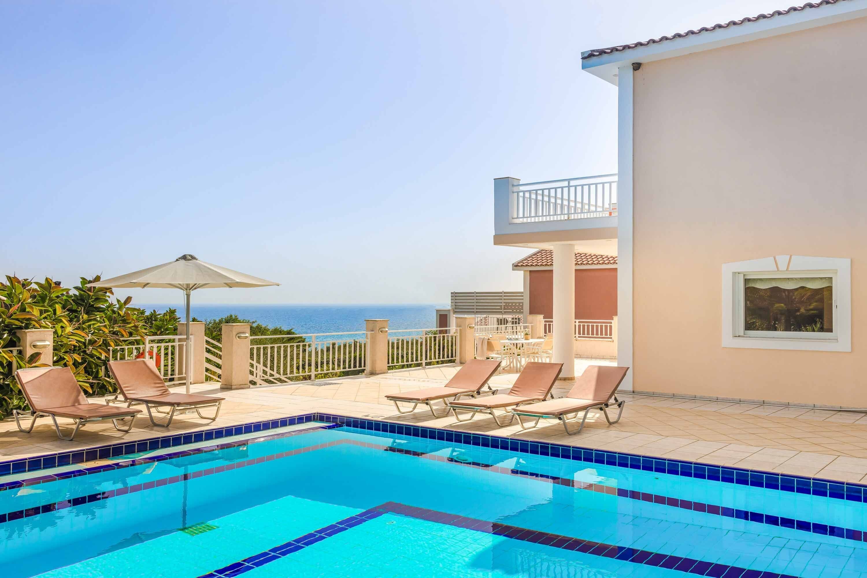 A swimming pool with lounge chairs and a view of the ocean.