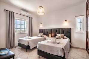 Een hotelkamer met twee bedden, een raam, een plafondventilator en een hanglamp.