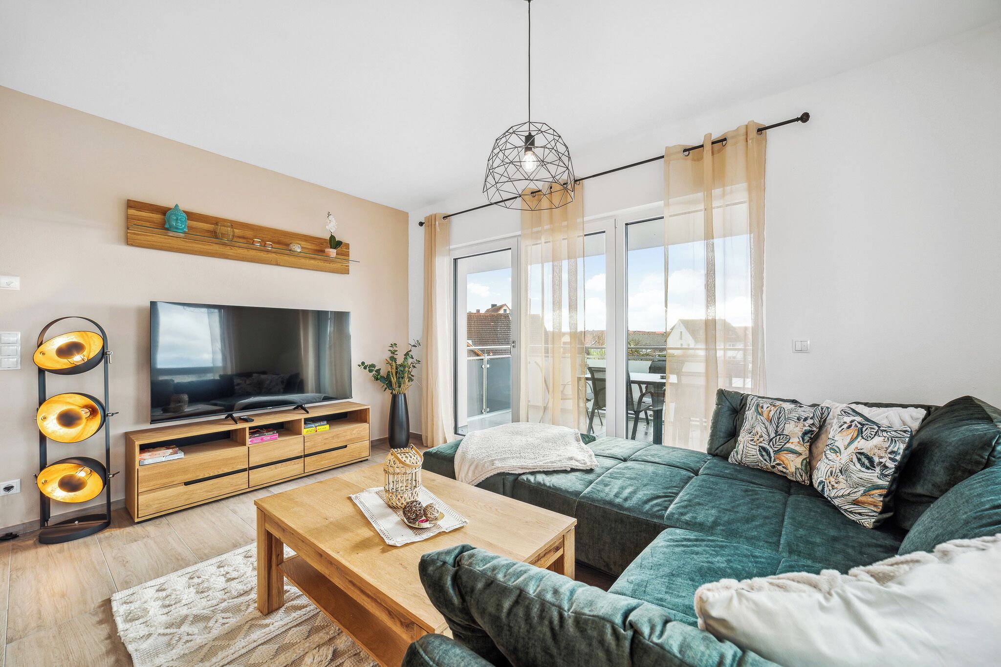 Ein modernes Wohnzimmer mit einer Couch, Fernseher, einem Holztisch und einer dekorativen Leuchte.